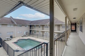 A multi-story building with a rooftop pool, outdoor seating, and a covered walkway.