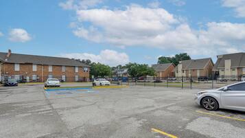 A parking lot with several cars, a blue handicapped parking space, and brick buildings in the background.