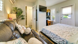 A bedroom with a bed, a leather couch, a TV, and a kitchen area. - 1 Mi to Vanderbilt Beach! Walkable Couples Haven (Naples)