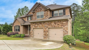 A two-story house with a stone facade, two garage doors, and a well-maintained lawn. - Spacious Group Hub! Walk to Tribble Mill Park (Lawrenceville)