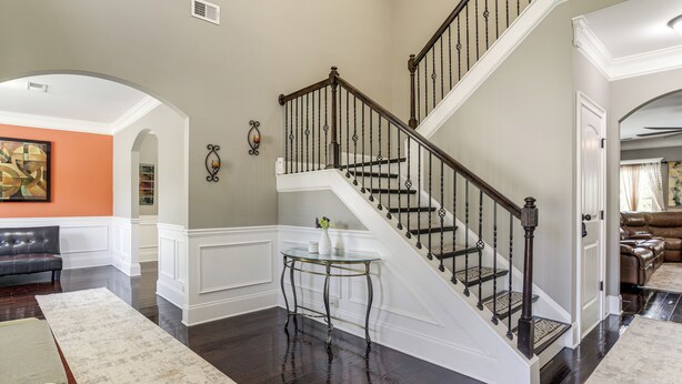 A staircase with a wooden handrail and black balusters, leading to a landing with a glass table and vase. - Spacious Group Hub! Walk to Tribble Mill Park (Lawrenceville)