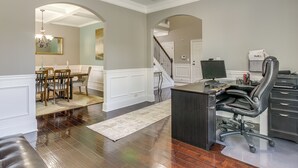 A home office with a desk, chair, and computer. There is a dining area with chairs and a table. The room has hardwood floors and white walls. - Spacious Group Hub! Walk to Tribble Mill Park (Lawrenceville)