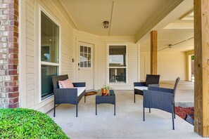A covered porch with wicker furniture, a small table, and a potted plant. - Modern Home Near Dfw: Work, Play + Relax! (Mansfield)