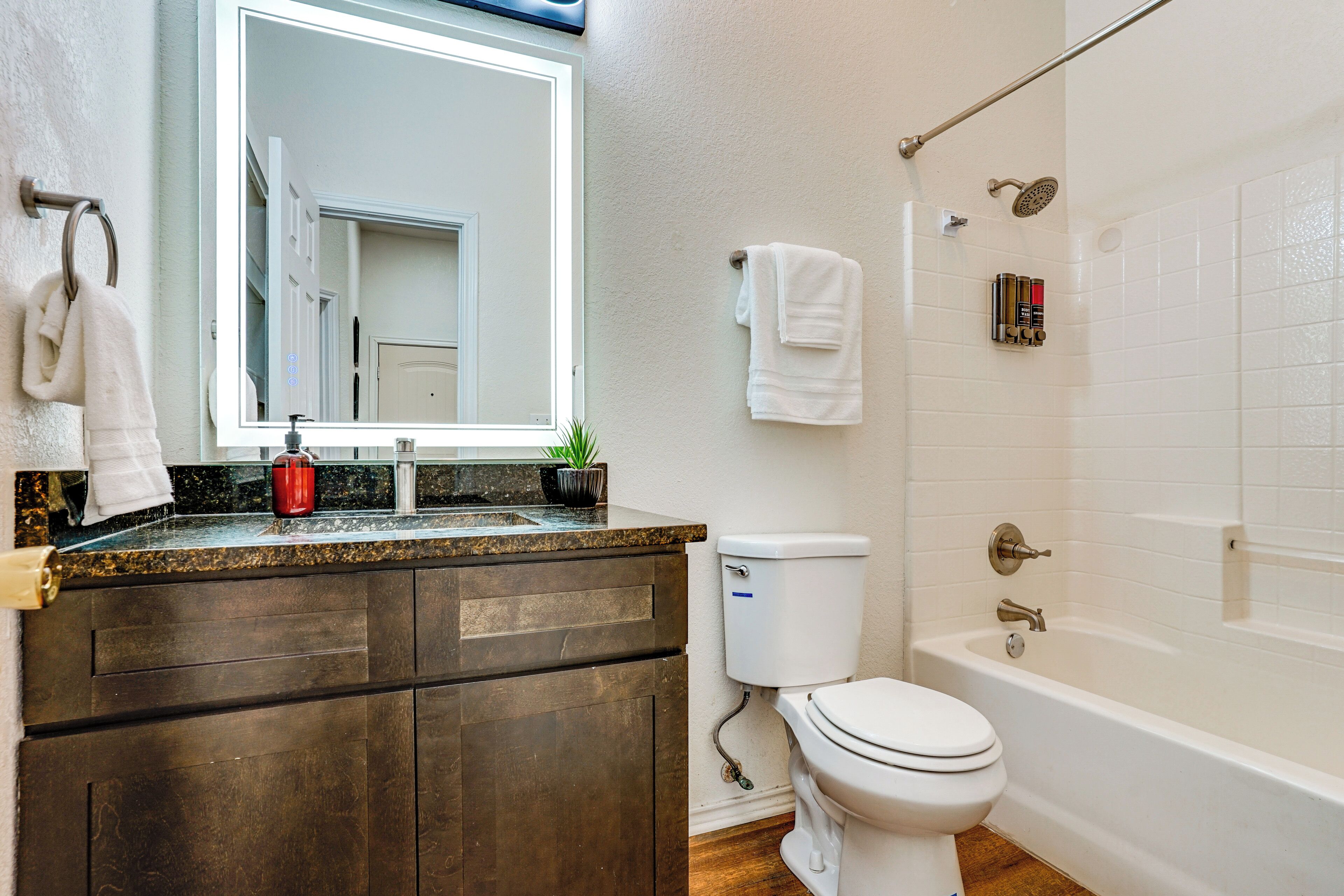 Une salle de bain équipée de toilettes, d’un lavabo, d’un miroir et d’une douche.