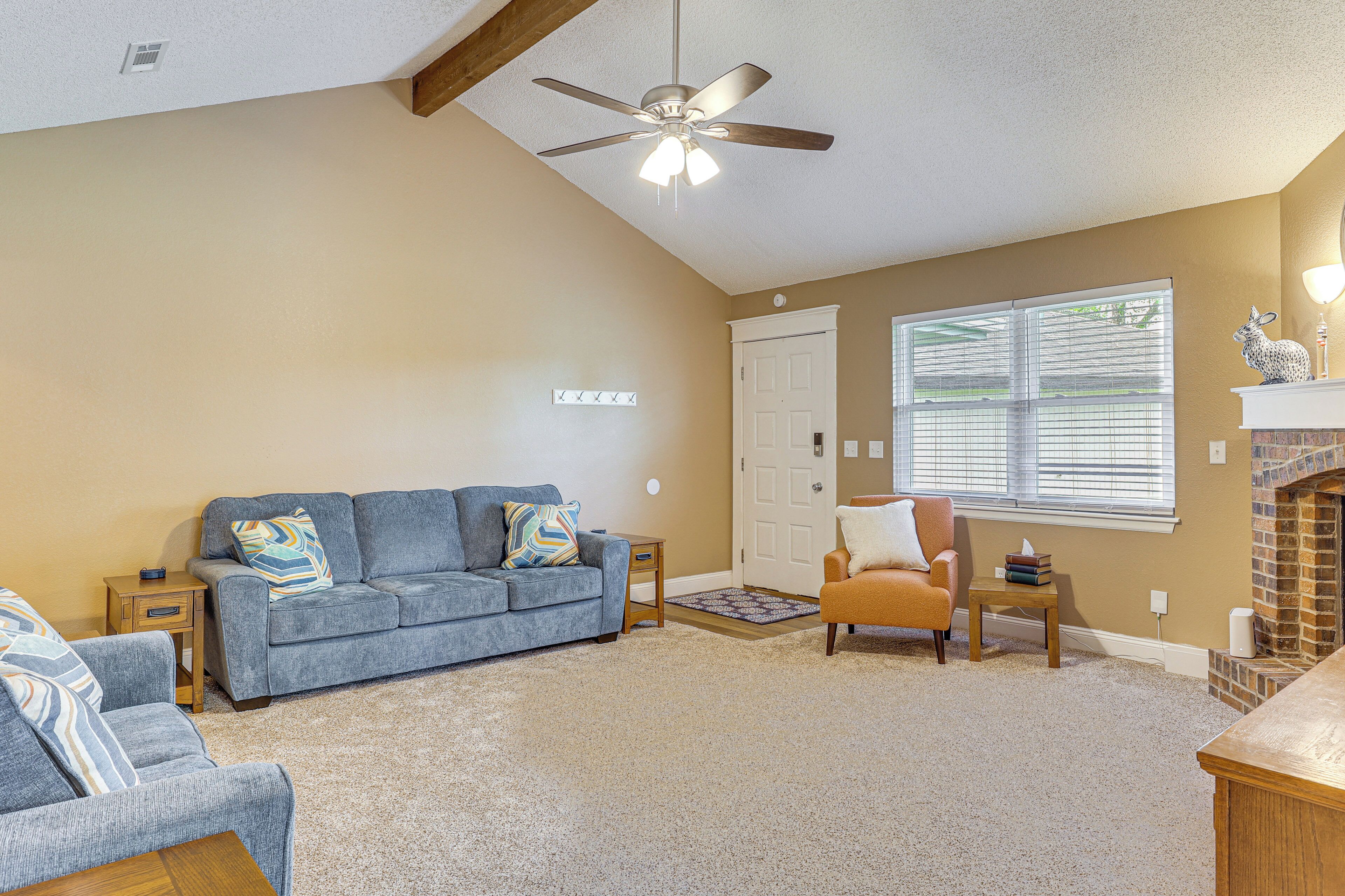 A living room with a blue sofa, a wooden coffee table, a fireplace, and a ceiling fan.