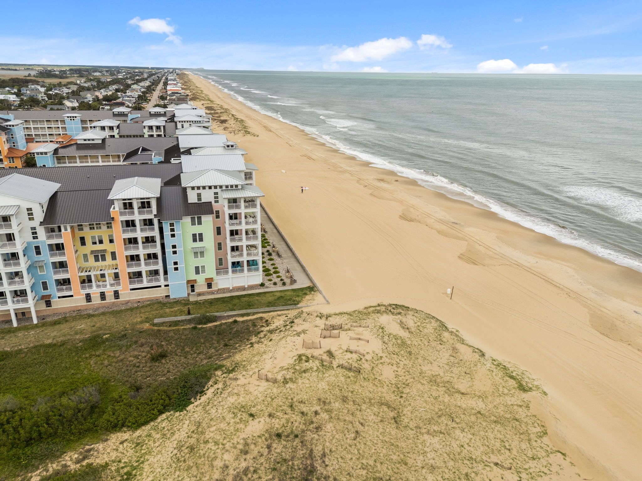 A coastal hotel with multiple floors, a beach view, and a sandy beach area.