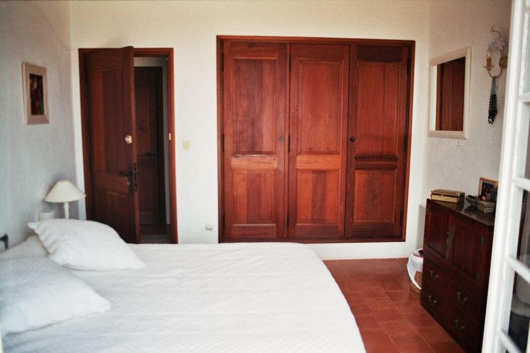 Un dormitorio con cama, armario, cómoda y espejo.
