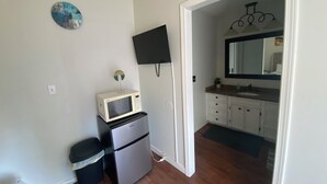 A compact kitchen with a microwave, refrigerator, and a small trash bin.