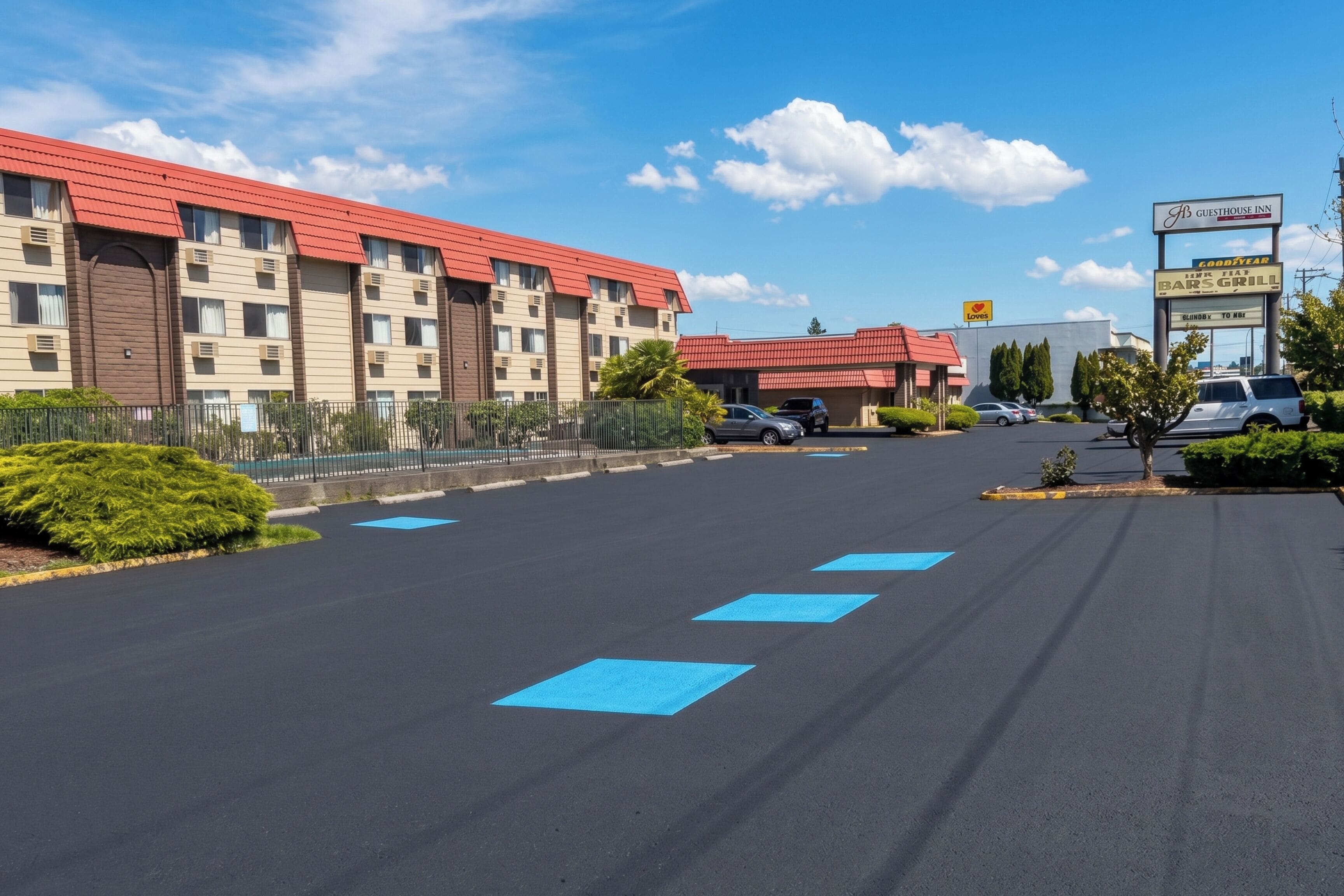 A hotel with a red roof, multiple floors, and a parking lot with blue directional arrows.
