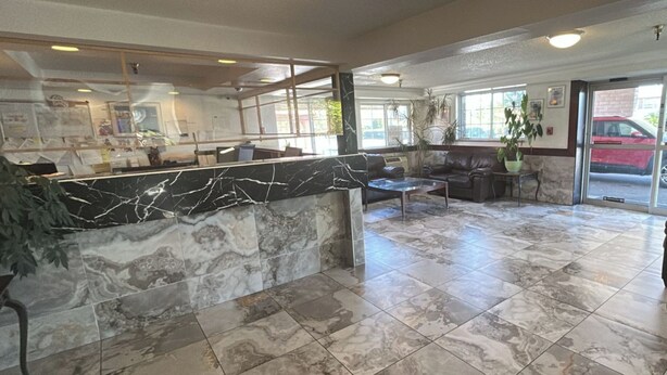 A lobby with a marble reception desk, seating area, and large windows.