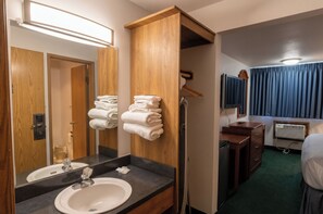 A hotel bathroom with a sink, mirror, towel rack, and a shower area. - Tacoma Port Inn Fife I-5 (Fife)