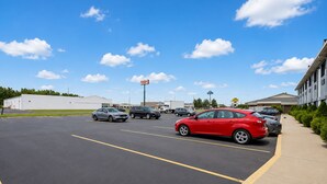 A parking lot with multiple cars, a building with a sign, and a clear sky. - Saint Joseph Inn & Suites Benton Harbor Near I-94 (Benton Harbor)