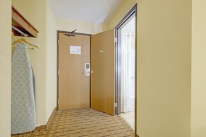 A hallway with a carpeted floor, a door with a peephole, and a hanging towel. - Saint Joseph Inn & Suites Benton Harbor Near I-94 (Benton Harbor)