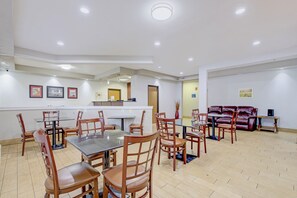 Un comedor amplio con varias mesas y sillas, una recepción y un área de descanso con un sofá.