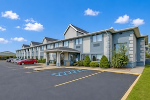 A hotel with a parking lot, a covered entrance, and a row of parked cars. - Saint Joseph Inn & Suites Benton Harbor Near I-94 (Benton Harbor)