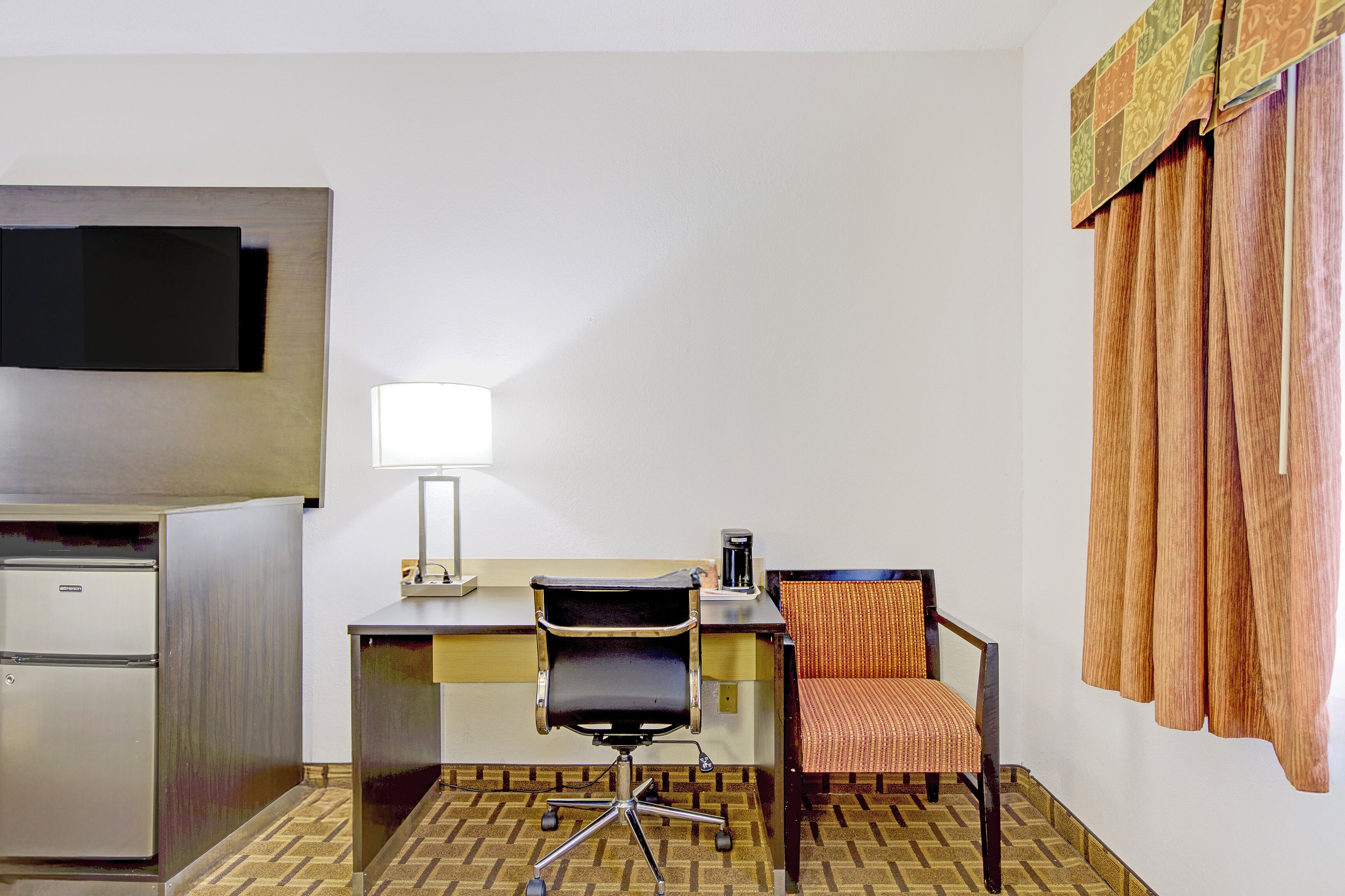 Une chambre d’hôtel équipée d’un bureau, d’une chaise, d’une télévision et d’une machine à café.
