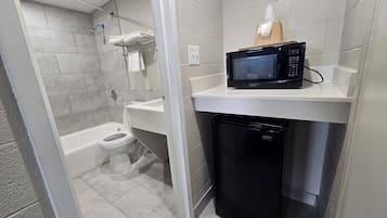 Ein kleines Badezimmer mit Toilette, Waschbecken und einer Mikrowelle auf einer Arbeitsfläche.