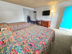 A hotel room with two beds, a desk, a chair, a dresser, a television, and a lamp. - Carolina Inn Anderson Clemson Area (Anderson)