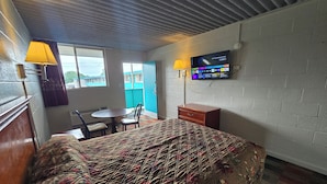 Una habitación de hotel con una cama, un escritorio, una silla, un televisor y una ventana.