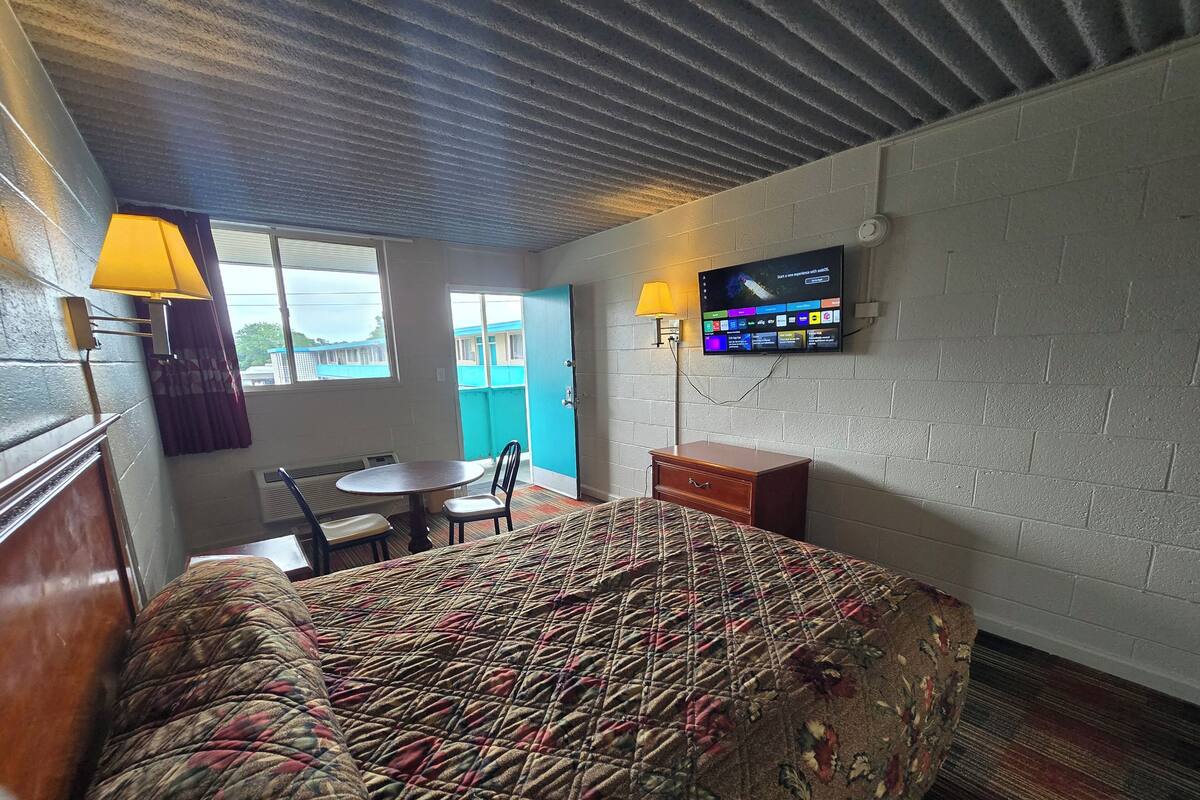 Habitació d'hotel amb un llit, escriptori, cadira, televisió i finestra.
