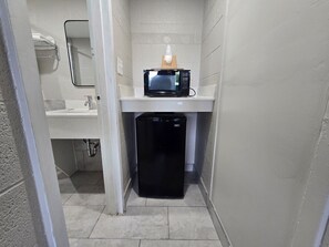 A compact bathroom with a sink, a microwave, and a small refrigerator. - Carolina Inn Anderson Clemson Area (Anderson)