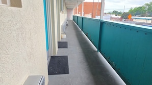 Un balcón cubierto con vistas a edificios y un cielo nublado.
