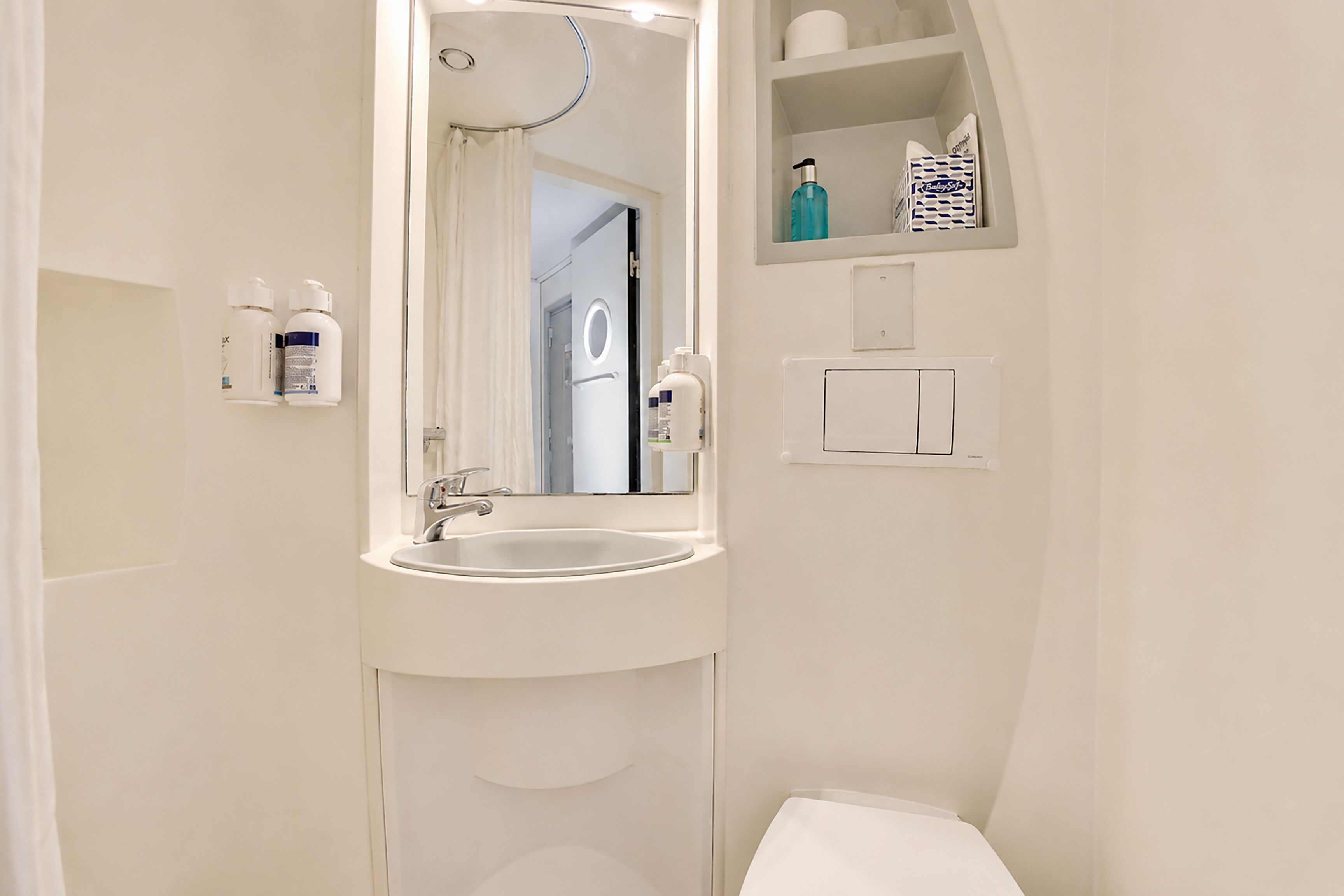 A bathroom with a sink, mirror, and storage shelves.
