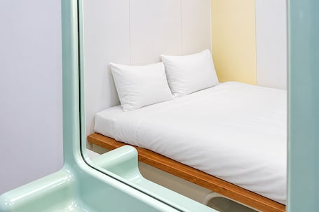 A bed with white bedding, a wooden frame, and a white pillow.