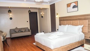 Une chambre d’hôtel avec un grand lit, un canapé, un bureau et une porte donnant sur une autre pièce.
