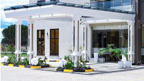 L’entrée d’un hôtel, avec un patio couvert, des colonnes et des plantes en pot.