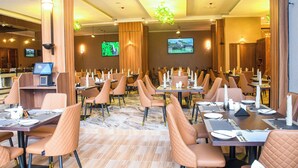 Un restaurant avec plusieurs tables, des chaises et un écran de télévision.
