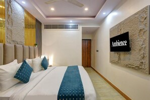 A hotel room with a bed, a wall-mounted TV, a ceiling fan, and a textured wall.
