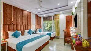 A hotel room with two beds, a ceiling fan, a TV, and a fruit basket. - Hotel Ambience (New Delhi)
