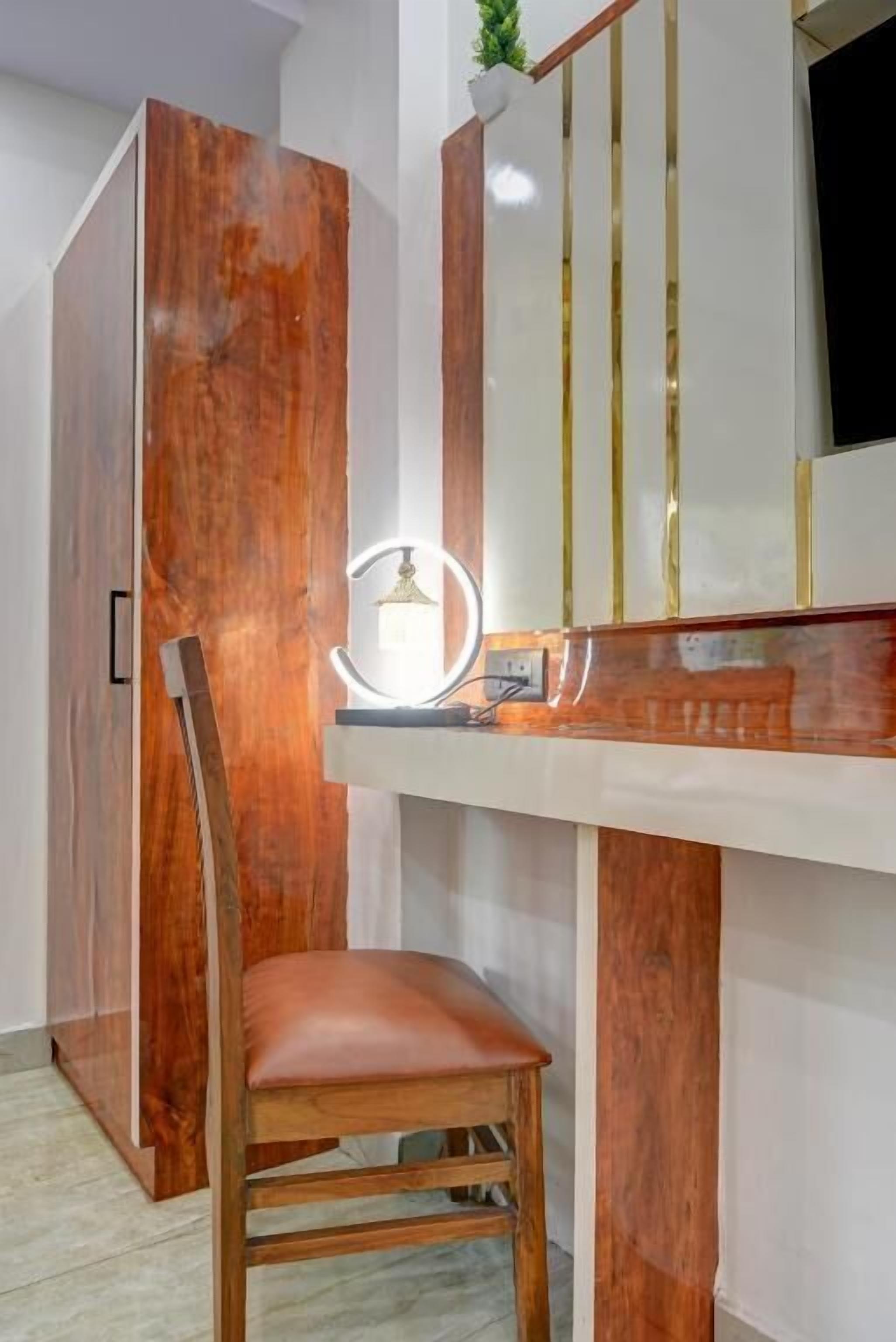 Una habitación con un armario de madera, un tocador con espejo e iluminación, y una silla de madera.
