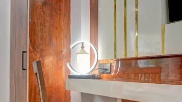 Una habitación con un armario de madera, un tocador con espejo e iluminación, y una silla de madera.