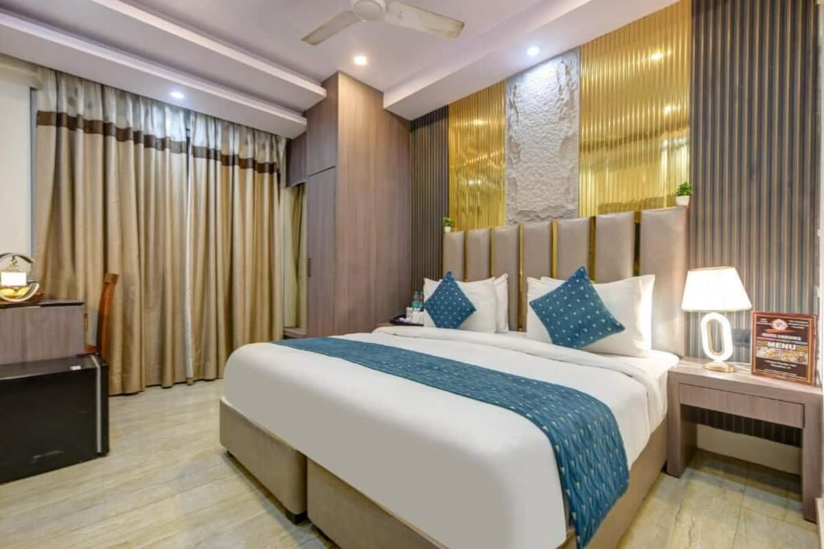Ein Hotelzimmer mit einem großen Bett, einem Schreibtisch, einem Sessel, einem Nachttisch mit Lampe und einem Deckenventilator.