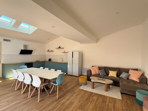 A modern kitchen with a dining area, a sofa, and a coffee table. - Village house with terrace and pool, only 20 minutes from the beach! (Lunel-Viel)