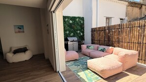 Un balcon avec un canapé, un barbecue et une clôture en bambou.