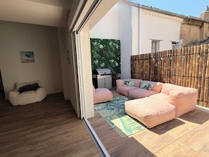 A balcony with a sofa, a grill, and a bamboo fence. - Village house with terrace and pool, only 20 minutes from the beach! (Lunel-Viel)