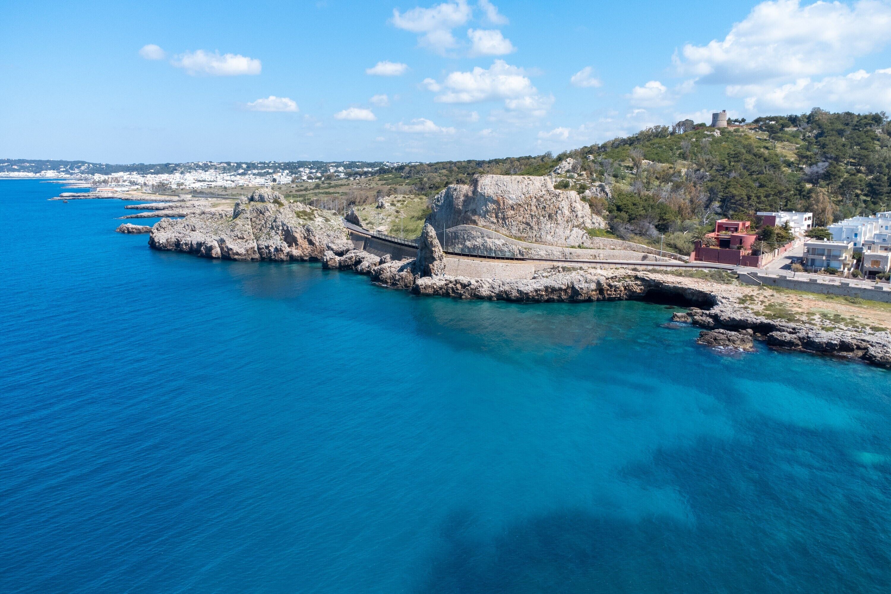A coastal town with a historic fort, clear blue sea, and modern buildings.