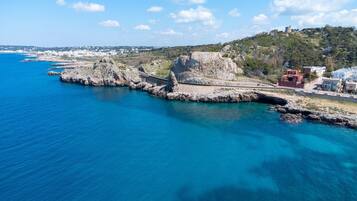 A coastal town with a historic fort, clear blue sea, and modern buildings.