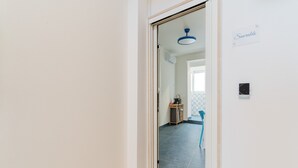 Ein Durchgang zu einem Raum mit Fliesenboden, einer Deckenleuchte und einem an der Wand montierten Thermostat.