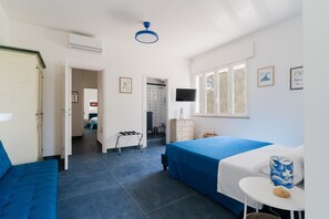 Une pièce comprenant un lit, un bureau, une chaise, un téléviseur et une fenêtre.