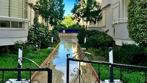 A residential building with a central pathway, surrounded by greenery and a clear sky. - ALANYAHOMES (Alanya)