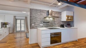 A modern kitchen with a stone backsplash, white cabinetry, and a built-in oven. - Luxury apartment near the cathedral of Seville (Sevilla)