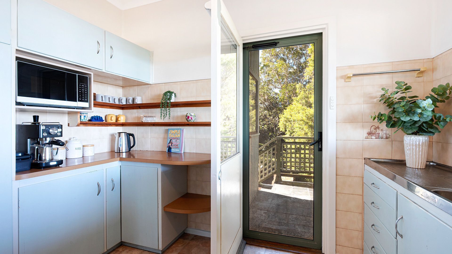 Una cocina compacta con microondas, cafetera y un pequeño comedor.