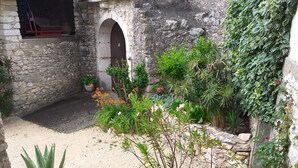 A courtyard with stone walls, a small bridge, and potted plants. - MAS PROVENCAL DE CARACTERE EN PIERRE. (Goudargues)