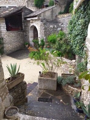 A courtyard with stone walls, a small bridge, and potted plants. - MAS PROVENCAL DE CARACTERE EN PIERRE. (Goudargues)