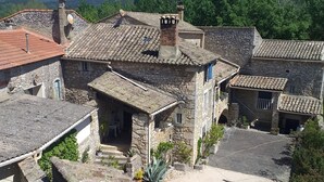 A traditional stone building with a tiled roof, a small garden area, and a clear view of the surrounding landscape. - MAS PROVENCAL DE CARACTERE EN PIERRE. (Goudargues)