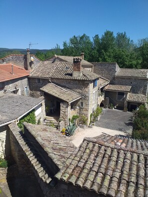 A traditional stone building with a tiled roof, a small garden area, and a clear view of the surrounding landscape. - MAS PROVENCAL DE CARACTERE EN PIERRE. (Goudargues)